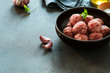 Raw ground meat meatballs in black bowl