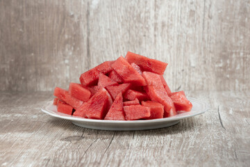 Watermelon pieces on white plate and wooden background