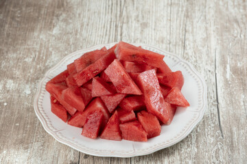 Watermelon pieces on white plate and wooden background