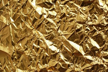 Gold crumpled foil paper background. Metallic foil paper wallpaper.