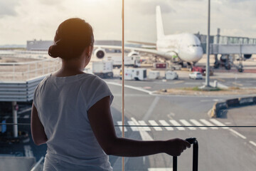 woman traveller waiting in airport for her flight, looking at the window, travel abroad by plane,...