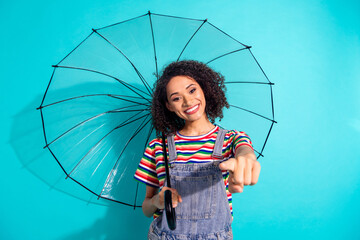 Photo of positive girl hold parasol umbrella point you finger isolated cyan color background