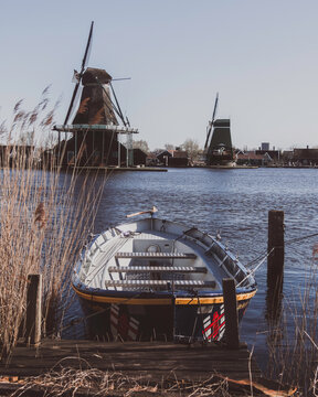 Small Boat Floating on Water with windmills behind