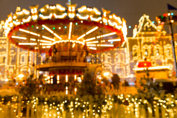 Defocused colorful merry-go-round on Christmas Fair in winter with lots of lights and bokeh on snowy evening