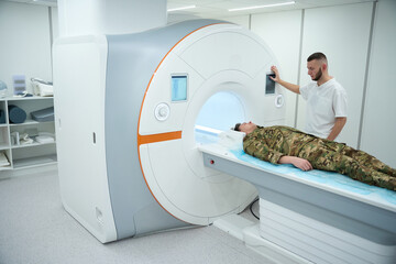 Healthcare worker preparing serviceman for magnetic resonance imaging screening