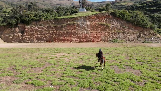 un joven y atractivo campesino montando un caballo caminando bajo la c&aacute;lida luz del sol durante el d&iacute;a. Concepto de viaje de estilo de vida saludable, turismo experiencial.rural,quechua,estilo de vida