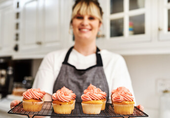 Woman, smile and tray with cupcakes in kitchen with fresh baked at home with pride for hobby. Small business, portrait and happiness in career with dessert or confidence for cooking in house bakery