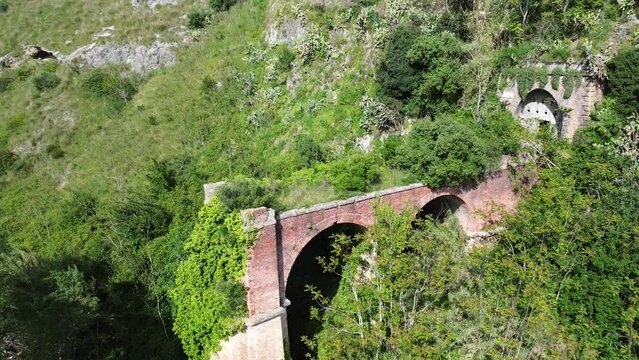 circular orbit aerial view of abandoned old railway bridge of Scalea City in south Italy surrounded by natural vegetation 3