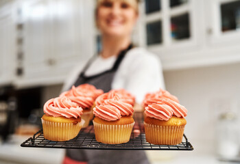 Tray, smile and woman with cupcakes in kitchen with fresh baked at home with pride for hobby. Portrait, happiness and small business in career with dessert or confidence for cooking in house bakery