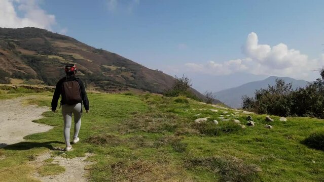 Mujer excursionista viajera caminando, aventurera con mochila sinti&eacute;ndose victoriosa frente a la monta&ntilde;a, al aire libre para la educaci&oacute;n de la naturaleza en vacaciones. Concepto de viaje,salto