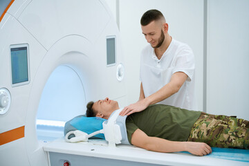 Technologist preparing serviceperson for MRI of upper extremity joint