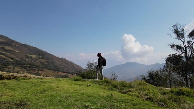 Mujer excursionista viajera caminando, aventurera con mochila sinti&eacute;ndose victoriosa frente a la monta&ntilde;a, al aire libre para la educaci&oacute;n de la naturaleza en vacaciones. Concepto de viaje,salto