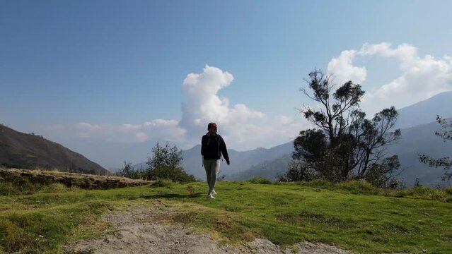Mujer excursionista viajera caminando, aventurera con mochila sinti&eacute;ndose victoriosa frente a la monta&ntilde;a, al aire libre para la educaci&oacute;n de la naturaleza en vacaciones. Concepto de viaje,salto