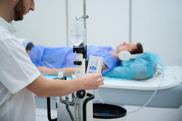 Technologist preparing man for contrast-enhanced lower extremity joint MRI