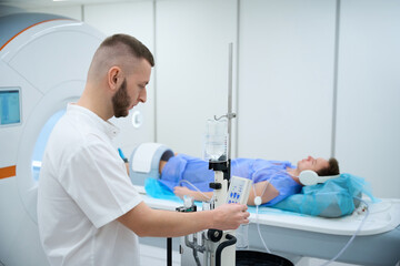 Doctor preparing man for contrast-enhanced lower extremity joint MRI