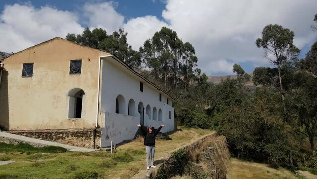 Mujer excursionista viajera, aventurera con mochila sinti&eacute;ndose victoriosa frente a la monta&ntilde;a, al aire libre para la educaci&oacute;n de la naturaleza en vacaciones. Concepto de viaje,casa quechua
