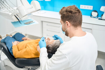 Skilled dental therapist conducting examination of patient oral cavity