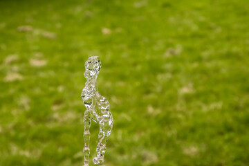 Water splash of park fountain closeup on green grass background