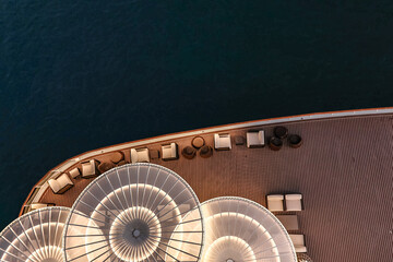 Lounge promenade deck on cruise ship. Interior of luxury cruise restaurant with tables and armchair in sunset at sea.