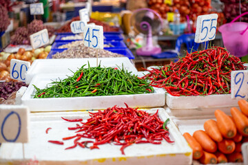 Asian vegetable market. Piles of hot chili peppers and other vegetables with price tags on the...