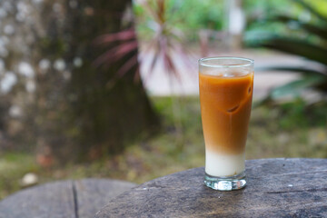 A glass of milk coffee served on a wooden table