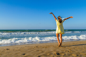 Carefree young happy stress free woman, feeling alive, free in nature with arms rased up, breathing...