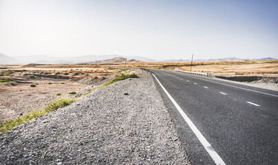 Asphalt road among hills and fields in the mountains of Tajikistan, a beautiful road in nature, panoramic landscape on a summer day