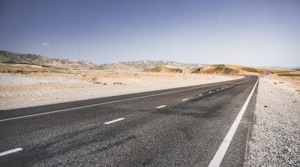 Asphalt road among hills and fields in the mountains of Tajikistan, a beautiful road in nature,...