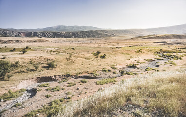 Spacious landscape view of mountains and hills with fields in Tajikistan, sunny summer day in nature