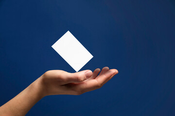 Woman with blank business card on blue background, closeup. Mockup for design