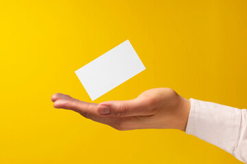 Woman with blank business card on yellow background, closeup. Mockup for design