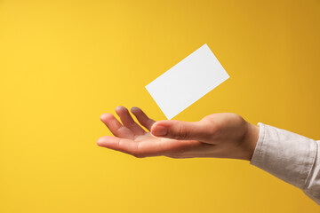 Woman with blank business card on yellow background, closeup. Mockup for design