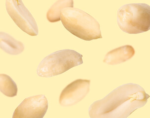 Many peanuts in air on beige background