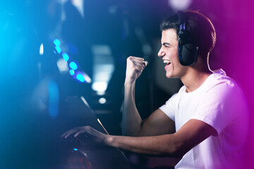 Neon, man and winner as pro gamer with playing on computer for online video games and excited. Headphones, esports and happy at home with victory on contest, challenge and competition on celebration