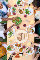 Vertical. Top view from above of unrecognizable people around meal table with wine glasses and food...