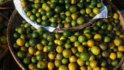 Limes in a bamboo basket at a traditional market stall. Some are green and some are yellow. Focus selected