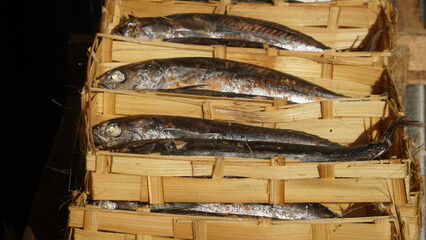Pindang fish in a bamboo basket at a traditional market stall. Focus selected