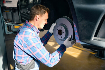 Young man installing brake disc on car