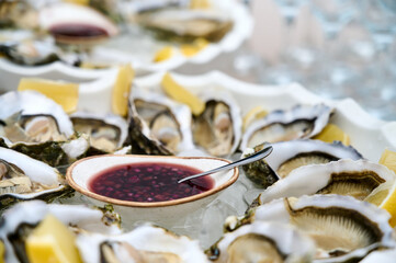 fresh open oysters in two plates with lemon slices and red sauce in a bowl. Close up shot.  © Микола Бордужак