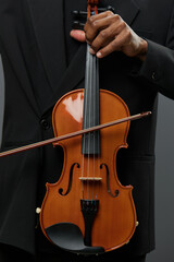 Fototapeta premium Close up of a man in suit holding violin on black background, classical music concept