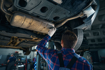 Male performing technical inspection of car suspension