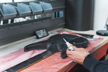 guitar repairman working on the guitar at the workshop, adding carbon fiber on a guitar at the...