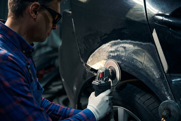 Skilled male working with front fender in tire fitting