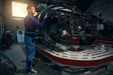 Young male installing fender on vehicle frame