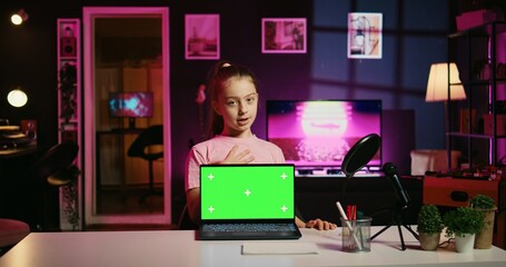 Young girl tech content creator filming technology review of green screen laptop, unboxing it and...