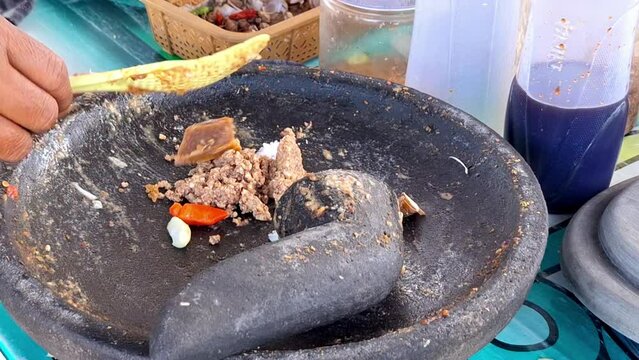 The process of making traditional Indonesian food, peanut sauce for Kupat Tahu, Pecel, etc. Using mortal and pestle.