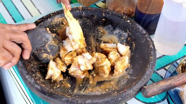 The process of making traditional Indonesian food, peanut sauce for Kupat Tahu, Pecel, etc. Using mortal and pestle.