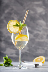 Hugo Spritz Cocktail with Mint, Lemon and Bamboo Straw on Concrete Background