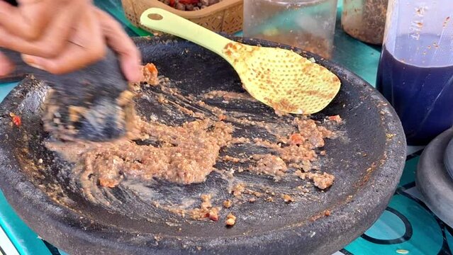 The process of making traditional Indonesian food, peanut sauce for Kupat Tahu, Pecel, etc. Using mortal and pestle.