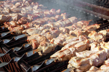 An outdoor barbecue grill is used to grill pork skewers over charcoal